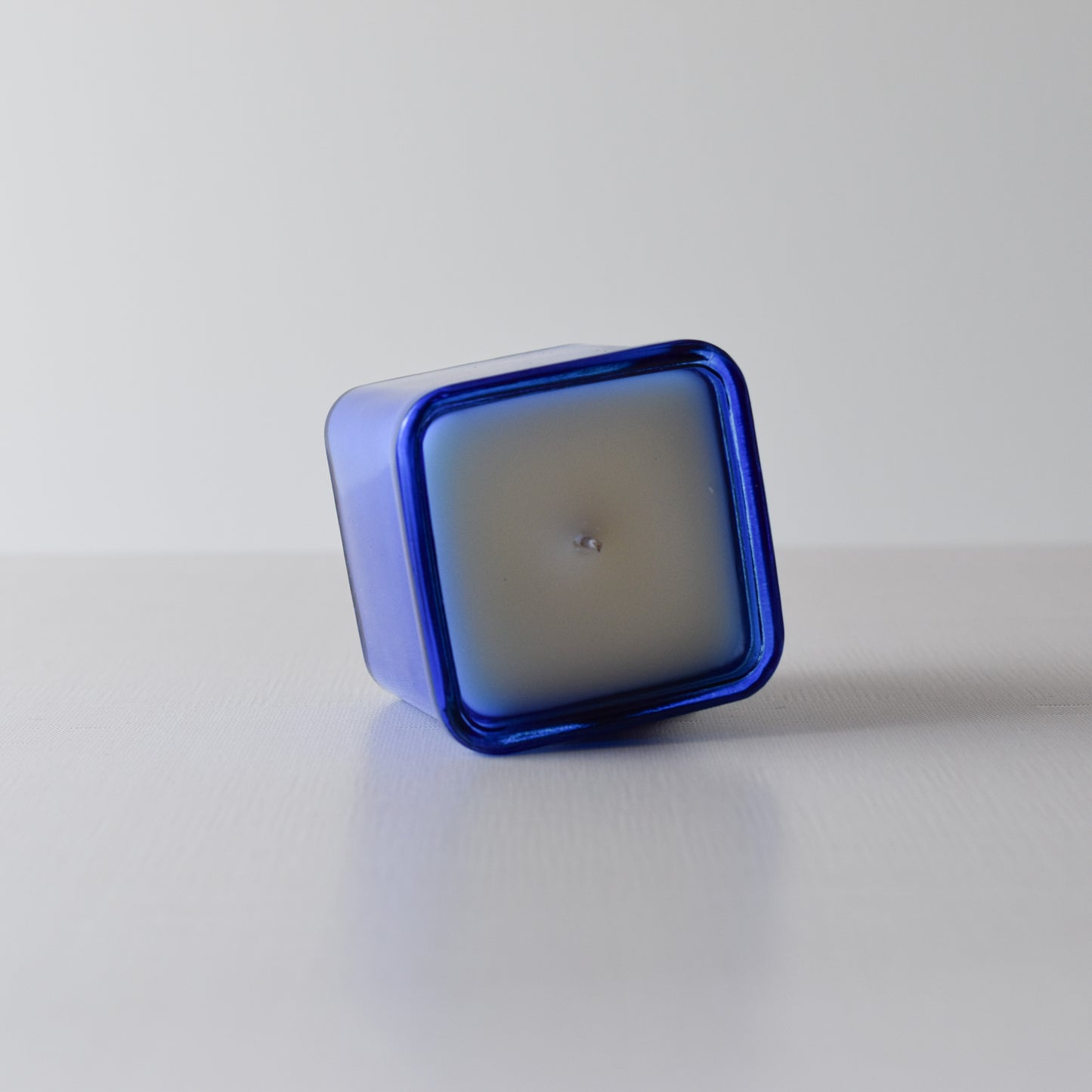 Square candle with blue container on a white background