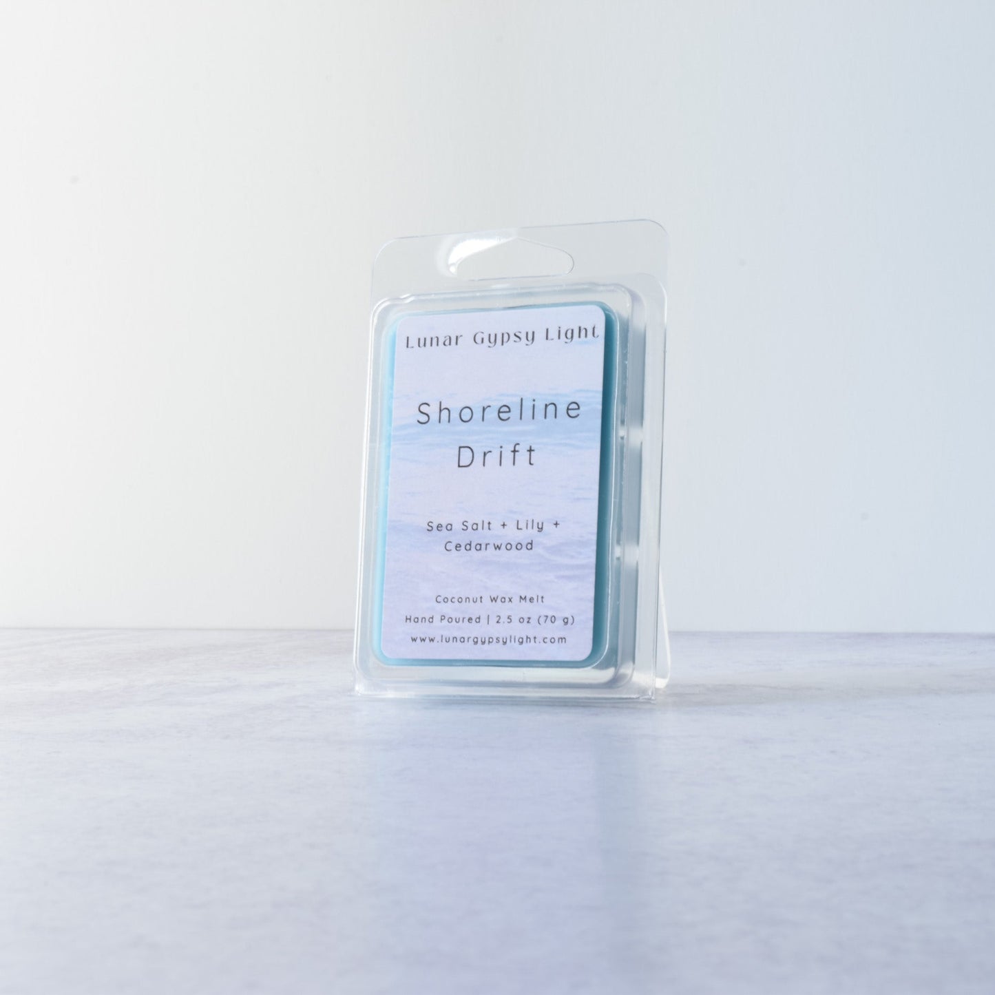Wax melt in a clear container with a label "Shoreline Drift" on a white background