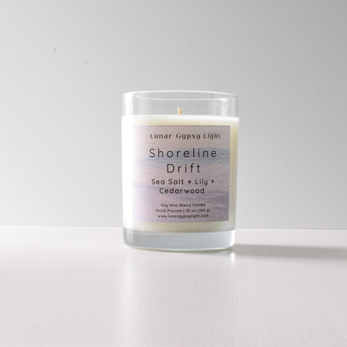 Candle labeled 'Shoreline Drift' with ingredients on a white background