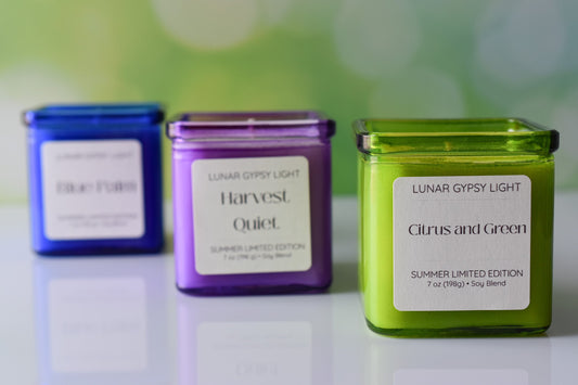 3 candles blue, violet and green with green sparkle background on white surface