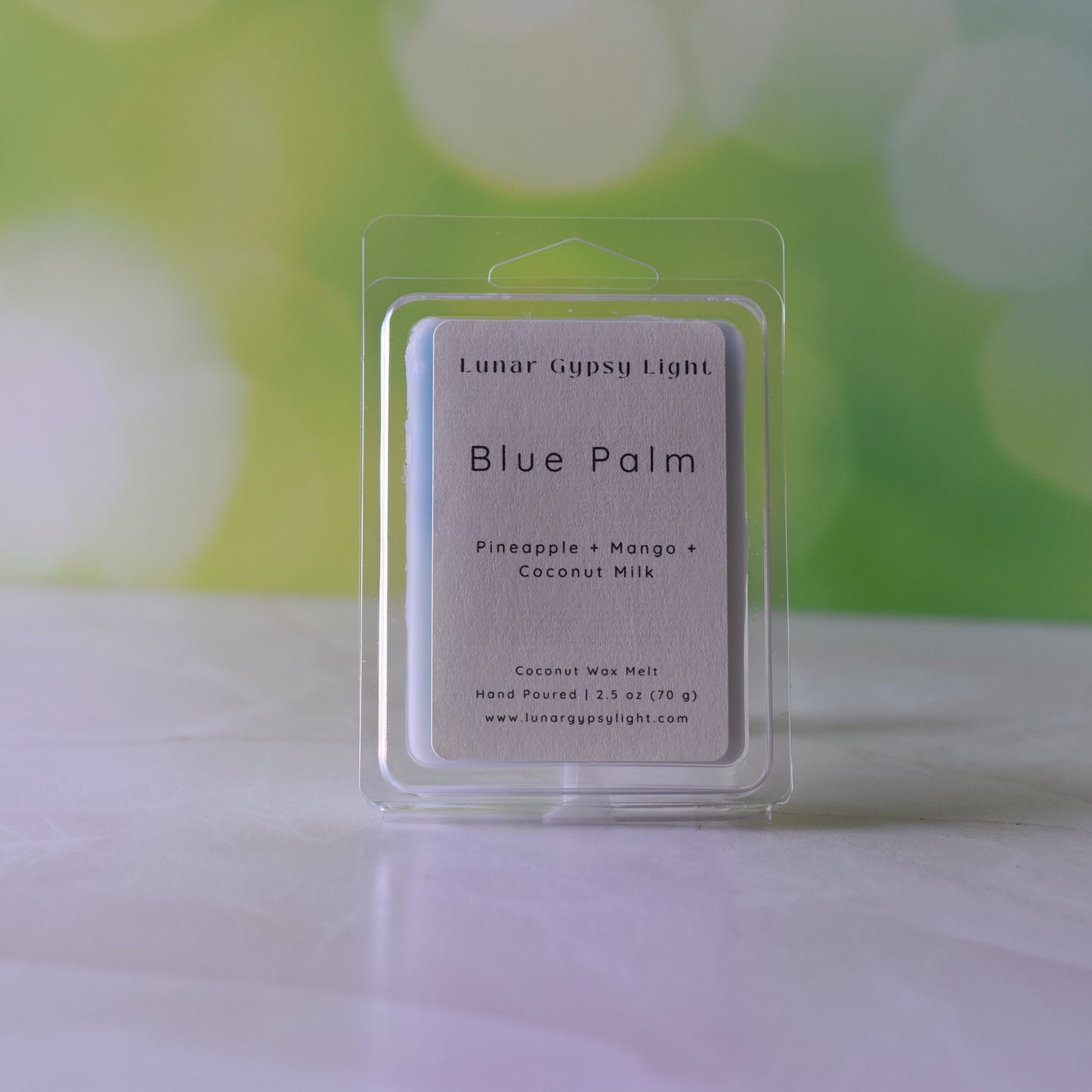 Packaged Wax melt labeled Blue Palm on white surface with green and yellow blurred background