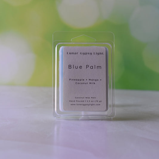 Packaged Wax melt labeled Blue Palm on white surface with green and yellow blurred background