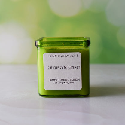 Green candle labeled 'Lunar Gypsy Light Citrus and Green' on a white surface with a blurred green background