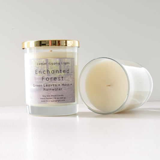 Candle labeled 'Enchanted Forest' with a gold lid on a white background
