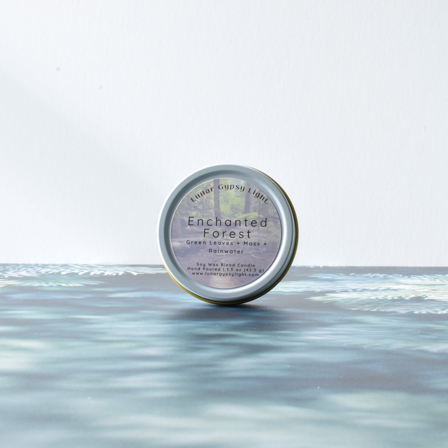 Mini Candle Tin labeled 'Enchanted Forest' on a fir inspired surface with a white background