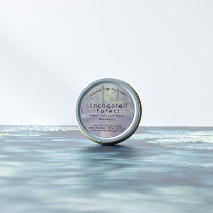 Mini Candle Tin labeled 'Enchanted Forest' on a fir inspired surface with a white background