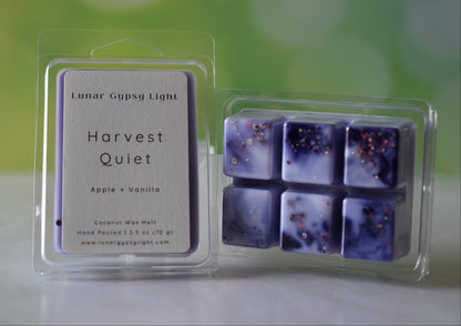 Packaged wax melts with 'Harvest Quiet' label on a blurred green and yellow background