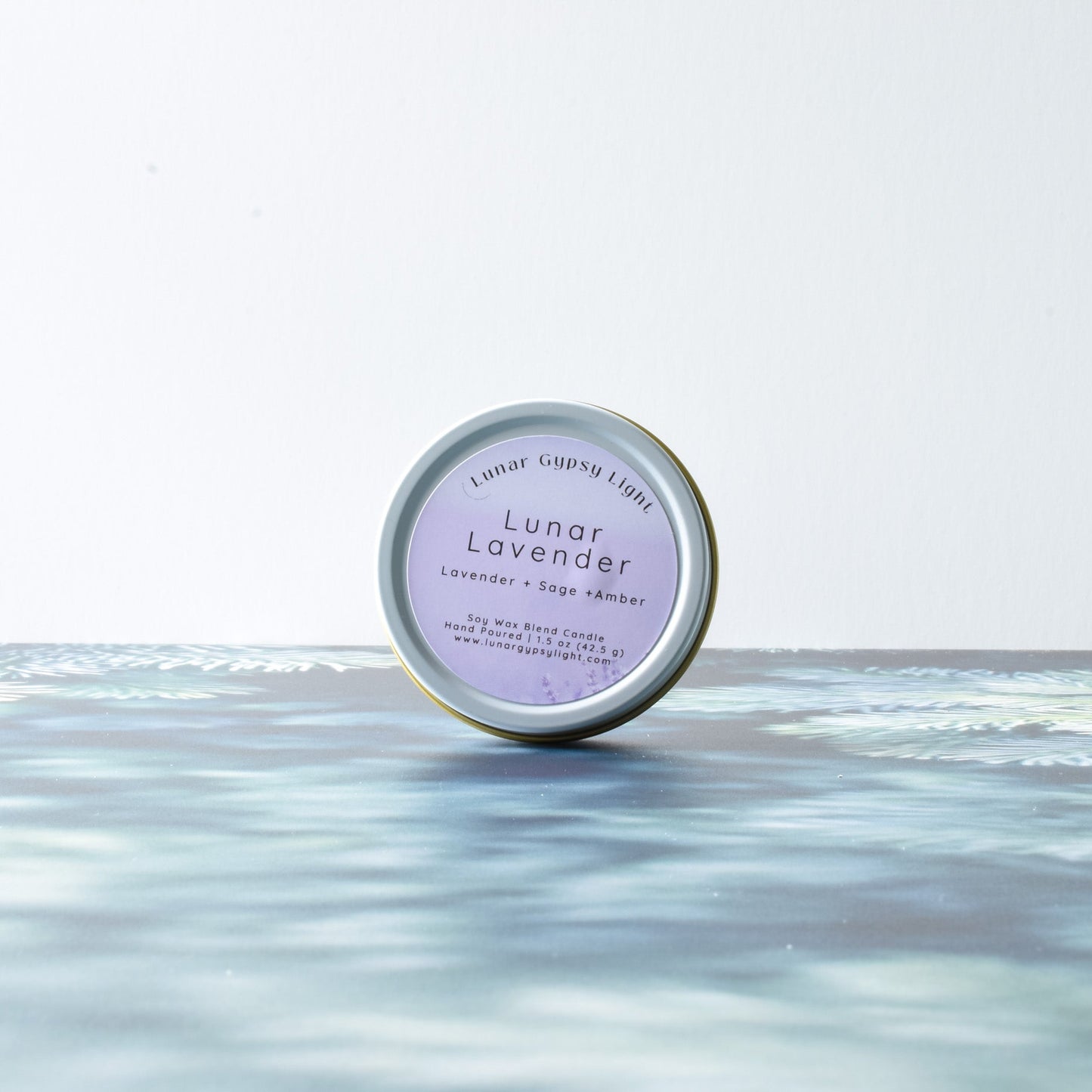 Lunar Lavender small candle tin product on a fir inspired surface with a white background