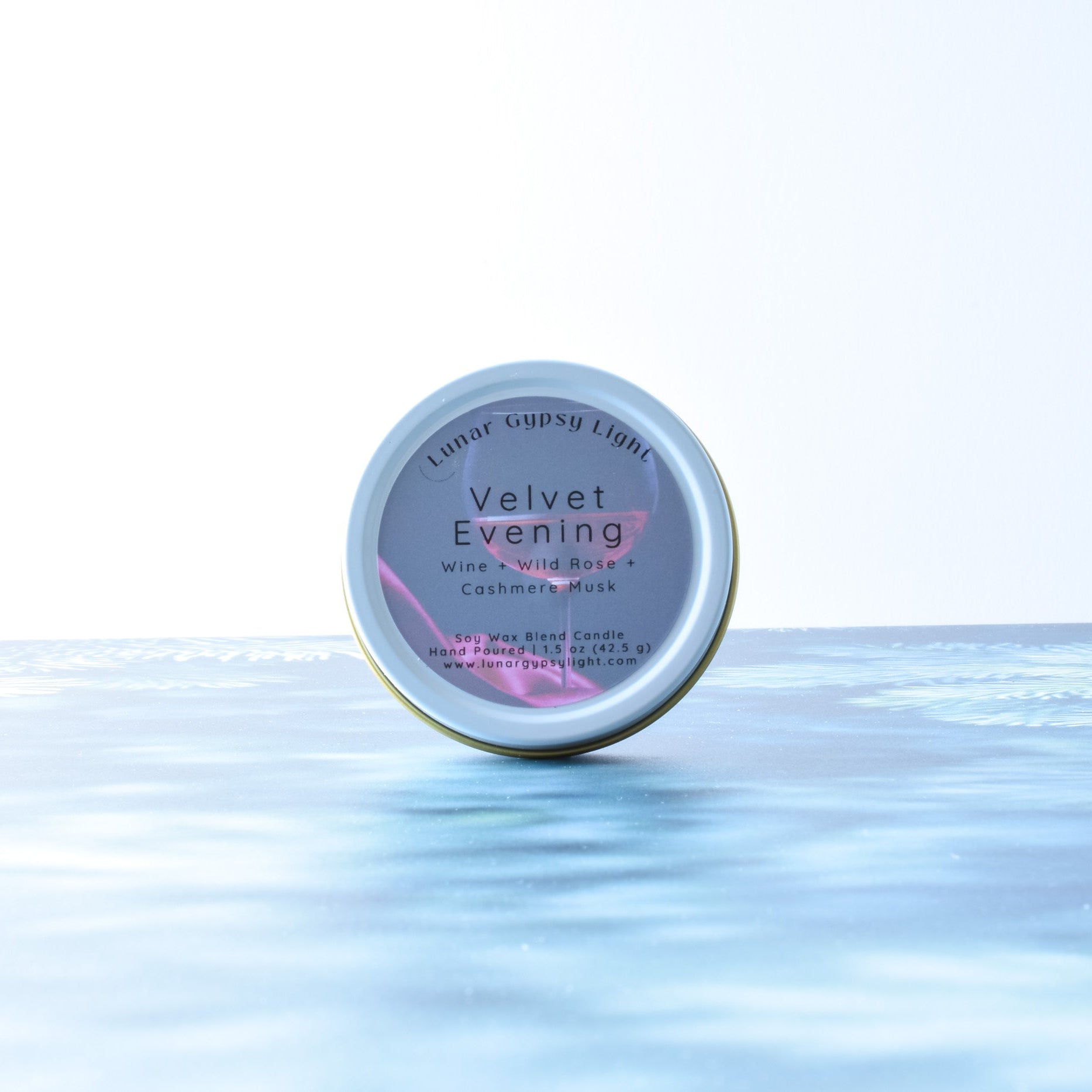 Mini Tin candle, labeled 'Velvet Evening', on a fir inspired surface with a white background.