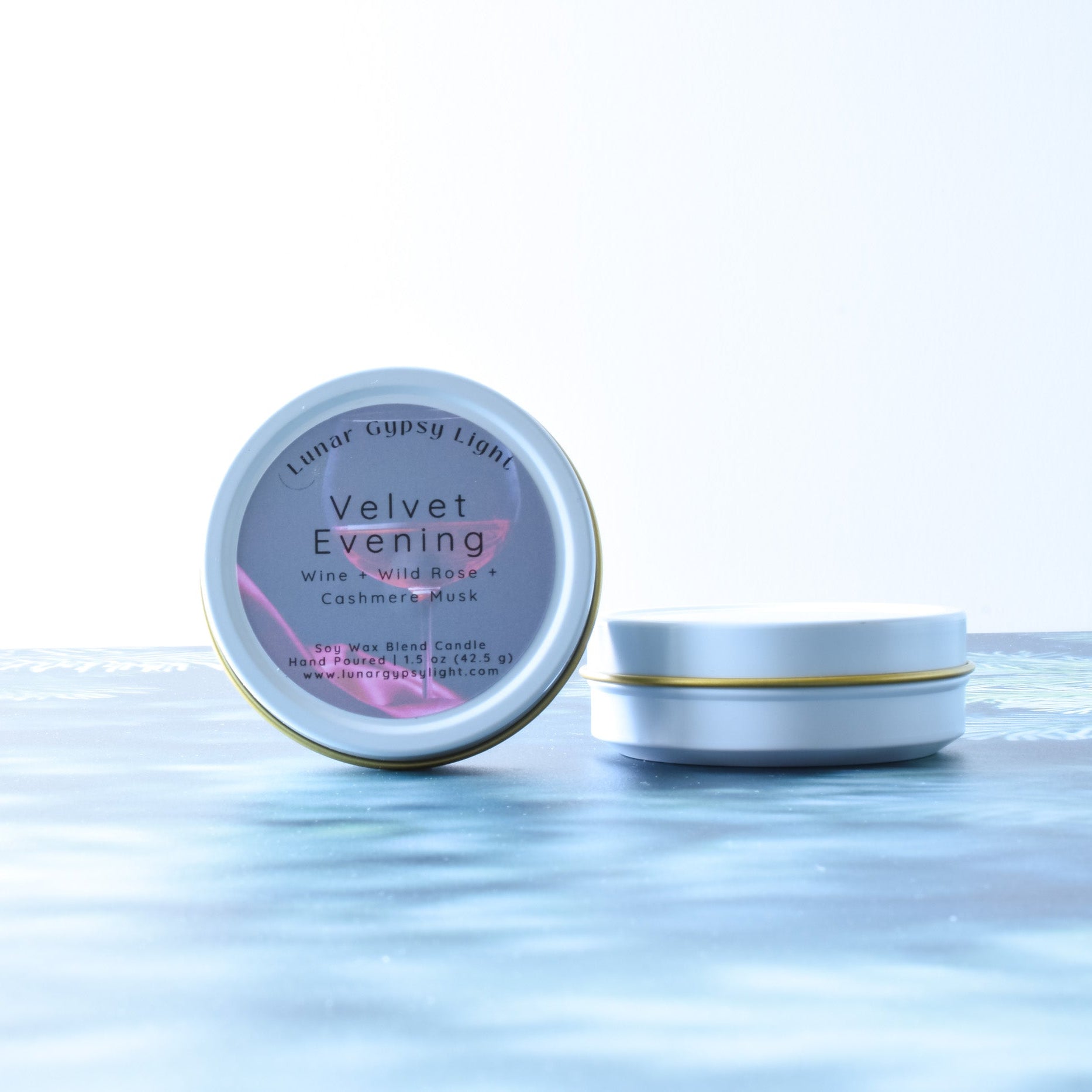 Mini Tin candle, labeled 'Velvet Evening', on a fir inspired surface with a white background.