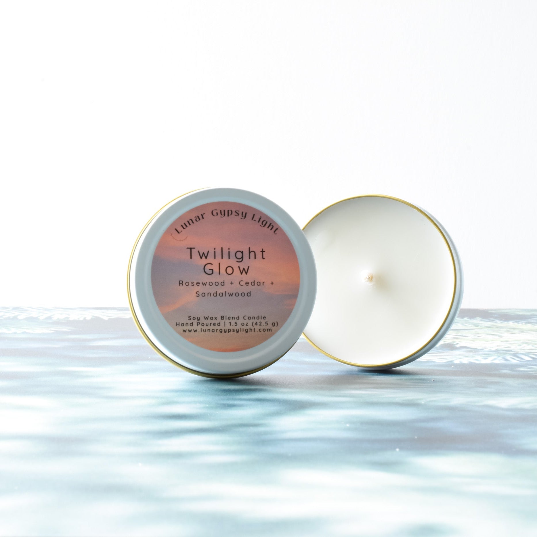Twilight Glow candle in a tin with a white background and fir inspired surface