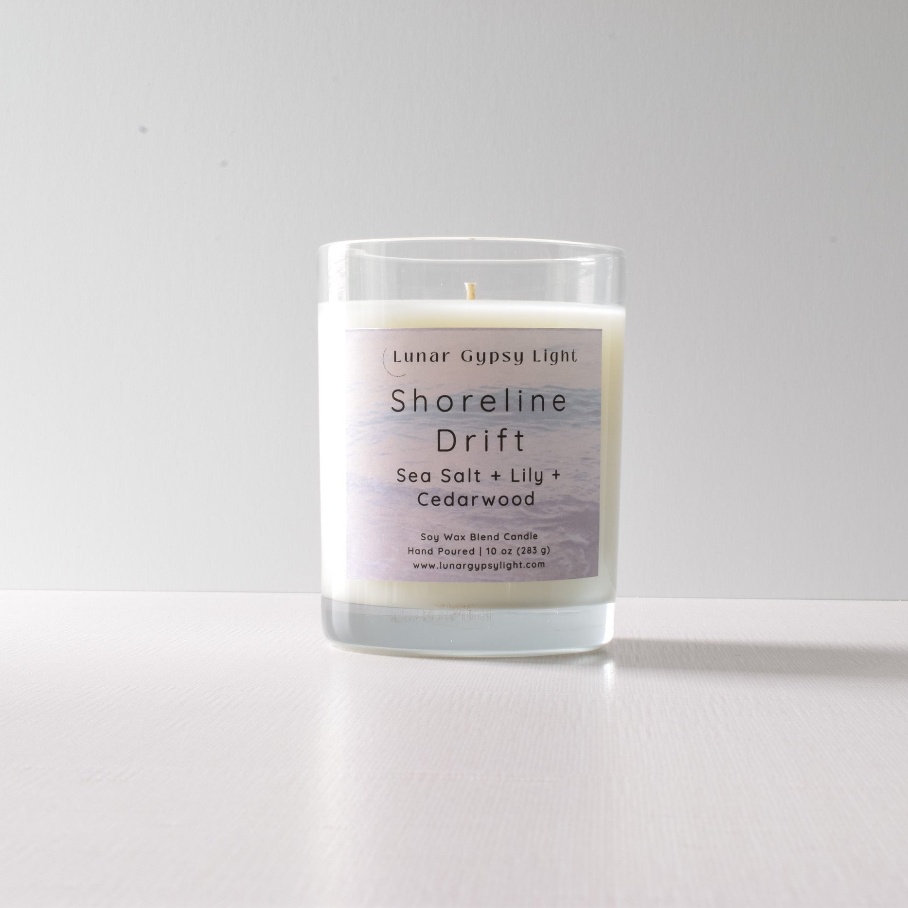 Candle labeled 'Shoreline Drift' with ingredients on a white background