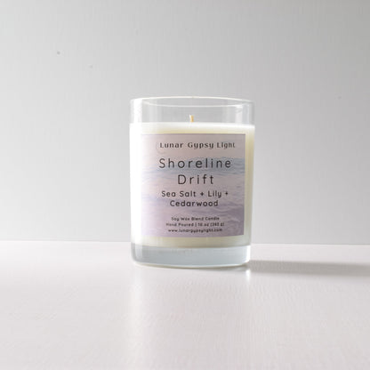 Candle labeled 'Shoreline Drift' with ingredients on a white background