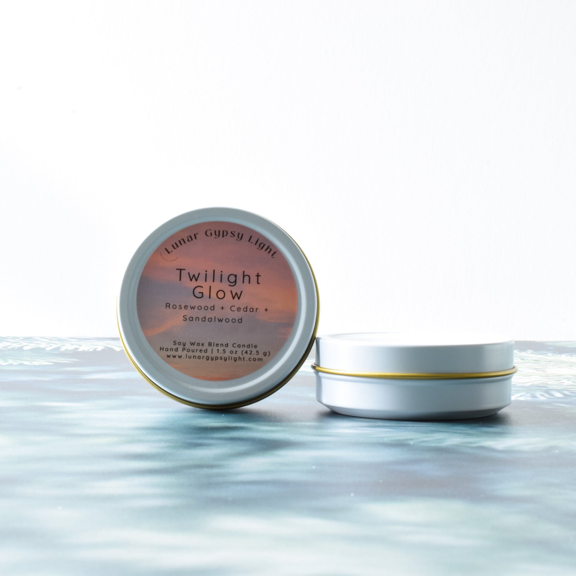 Mini candle tins of 'Twilight Glow' on a fir isnpired surface with a white background